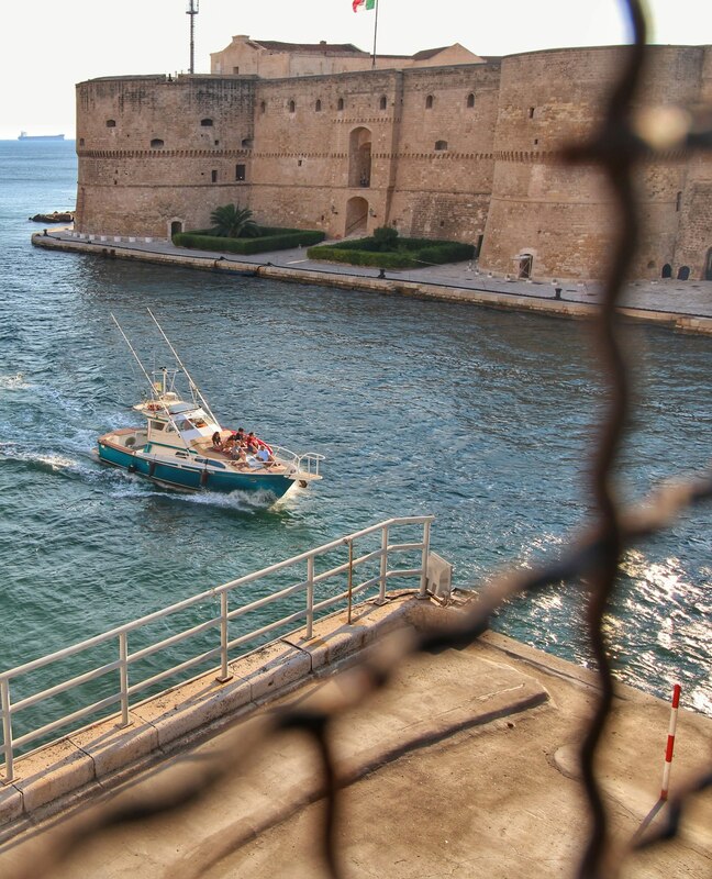 Barche da pesca ormeggiate nel porto di Brindisi, viste dietro una rete
