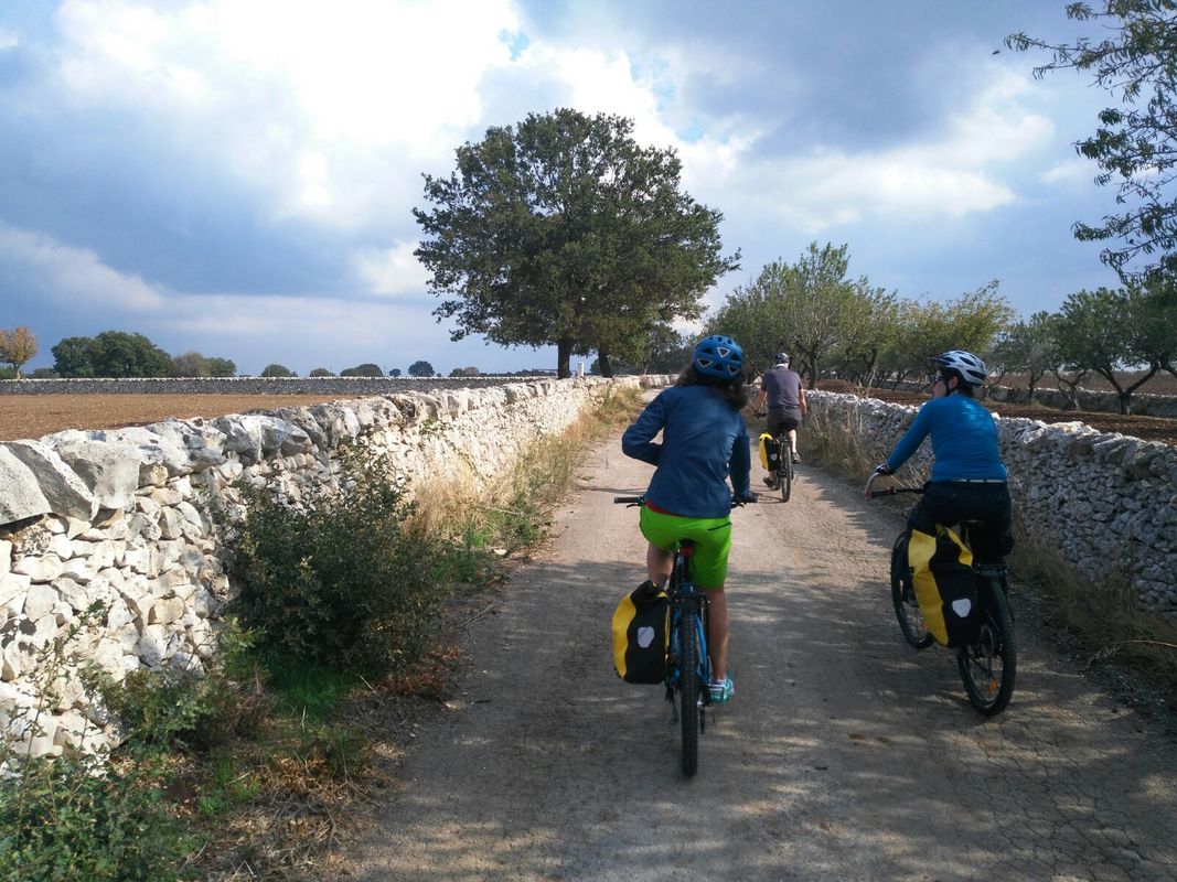 Cicloturisti con le borse su una strada di campagna in Valle d'Itria